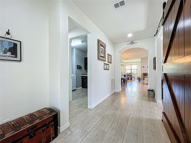 hallway with arched walkways, visible vents, and baseboards