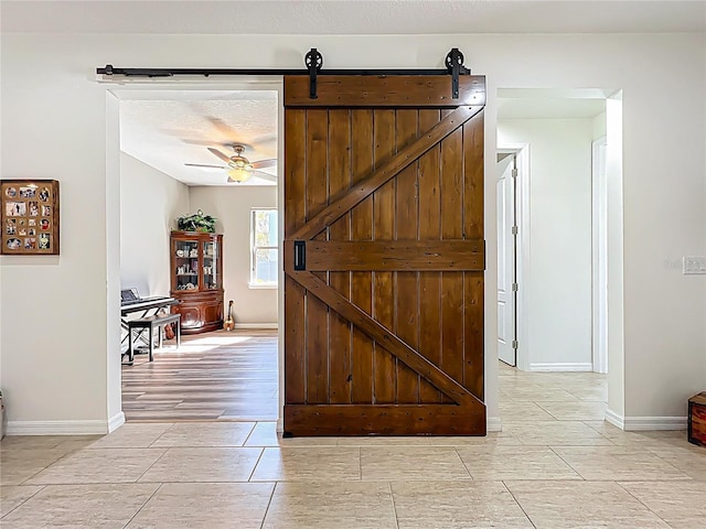 interior space featuring baseboards, a ceiling fan, and a barn door