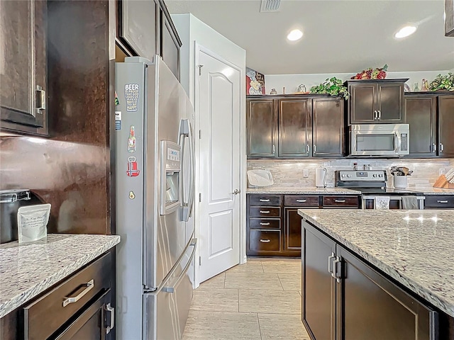 kitchen with light stone counters, tasteful backsplash, recessed lighting, stainless steel appliances, and dark brown cabinetry