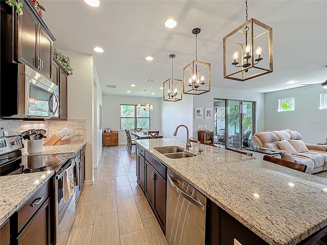 kitchen featuring visible vents, a sink, tasteful backsplash, open floor plan, and appliances with stainless steel finishes