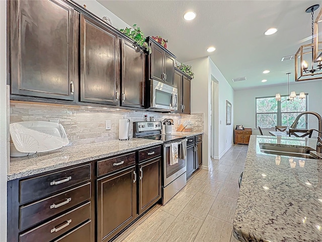 kitchen featuring visible vents, appliances with stainless steel finishes, light stone countertops, and a sink