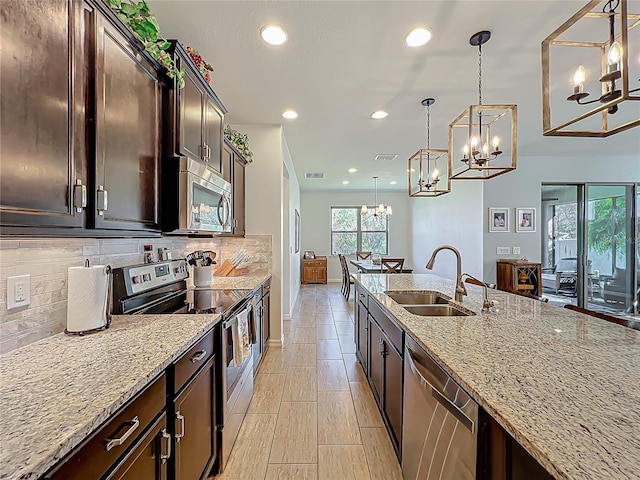 kitchen featuring backsplash, light stone countertops, appliances with stainless steel finishes, and a sink