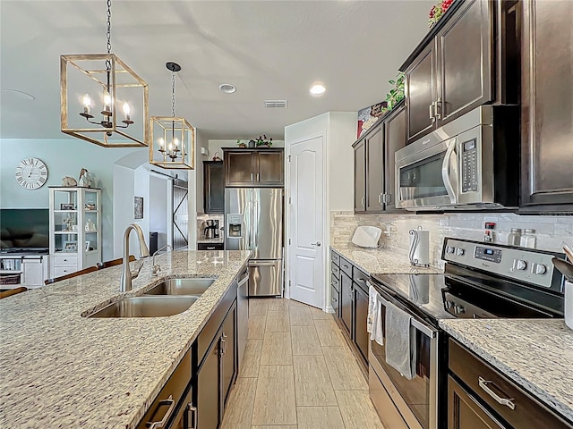 kitchen with visible vents, a sink, tasteful backsplash, stainless steel appliances, and dark brown cabinetry