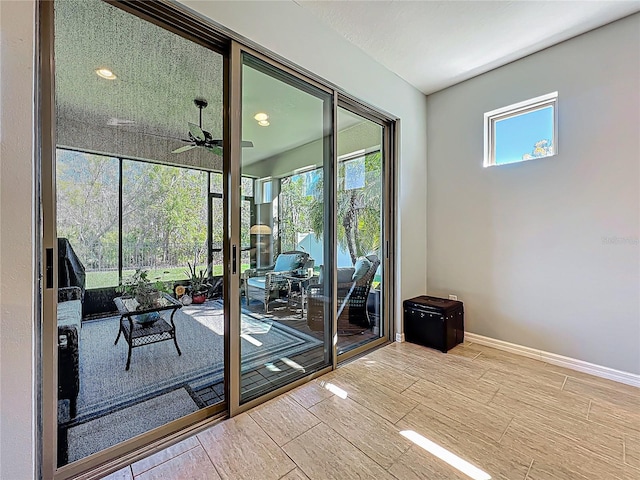 doorway to outside with wood finished floors, a ceiling fan, and baseboards