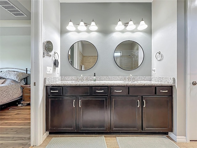 ensuite bathroom with wood finished floors, visible vents, double vanity, a sink, and ensuite bathroom