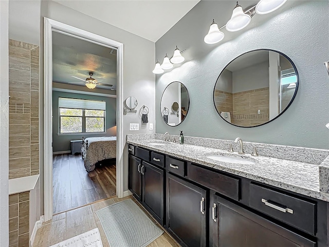 ensuite bathroom featuring a sink, connected bathroom, wood finished floors, and double vanity