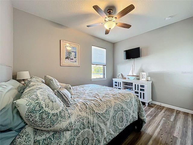 bedroom with a ceiling fan, wood finished floors, and baseboards