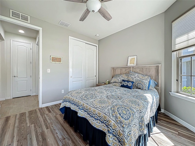 bedroom featuring wood finished floors, visible vents, and a closet