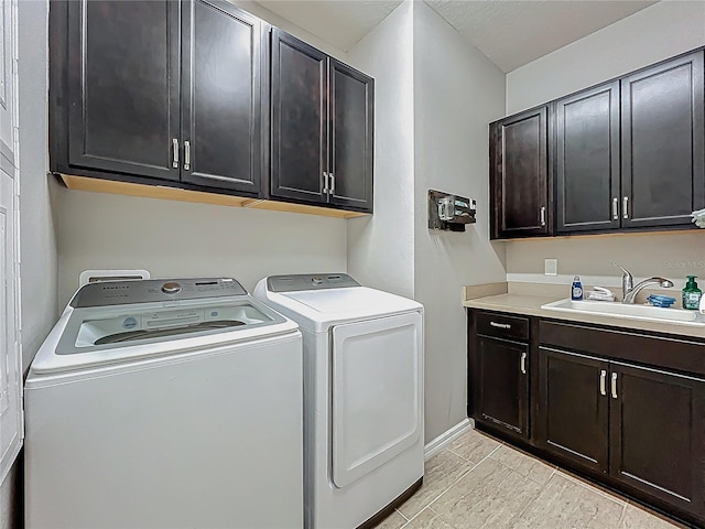 washroom with a sink, baseboards, cabinet space, and washing machine and clothes dryer