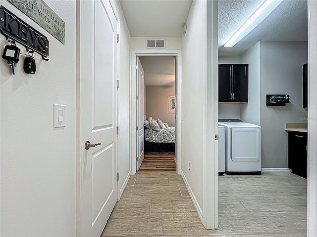 hallway with visible vents, baseboards, and separate washer and dryer