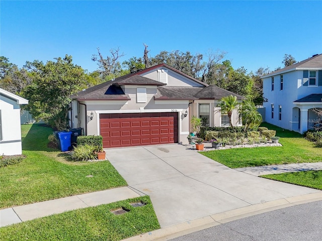 view of front facade featuring a front yard, a garage, driveway, and stucco siding