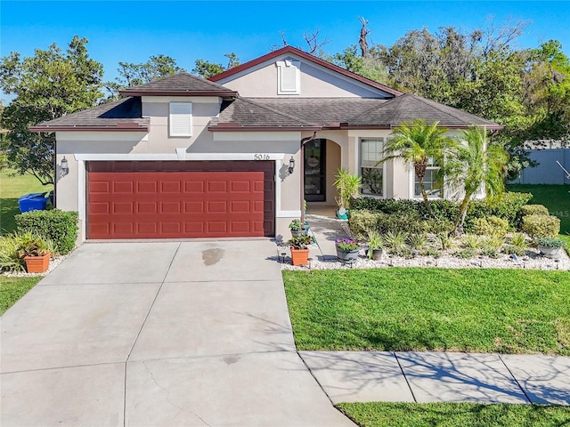 view of front of house featuring stucco siding, an attached garage, driveway, and a front yard