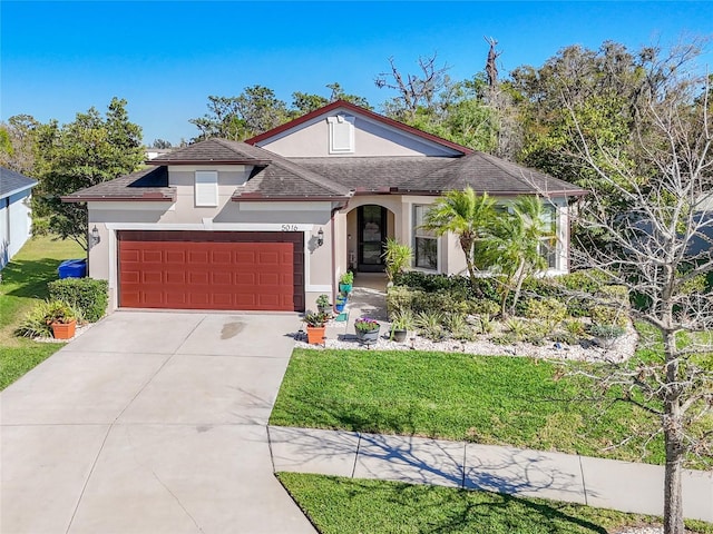 view of front of property featuring stucco siding, a front lawn, an attached garage, and driveway