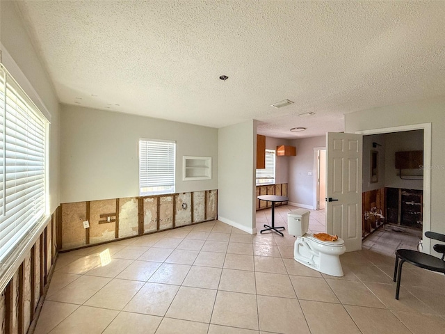 spare room with a healthy amount of sunlight, light tile patterned flooring, and a textured ceiling