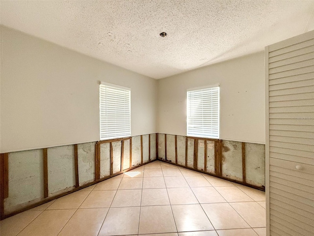 empty room with a textured ceiling and tile patterned floors