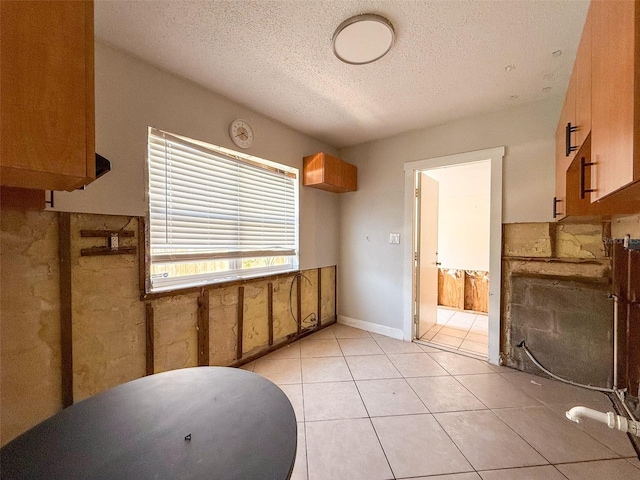 kitchen with light tile patterned floors, baseboards, and a textured ceiling