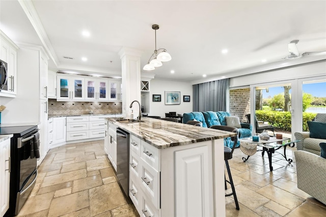 kitchen featuring open floor plan, range with electric stovetop, a sink, and stone tile floors