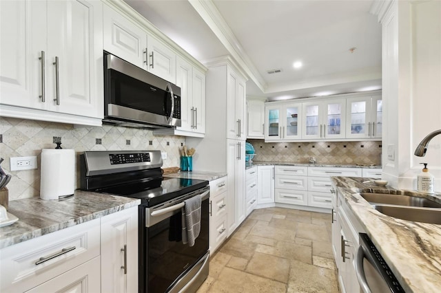 kitchen featuring visible vents, white cabinets, stainless steel appliances, stone tile flooring, and a sink