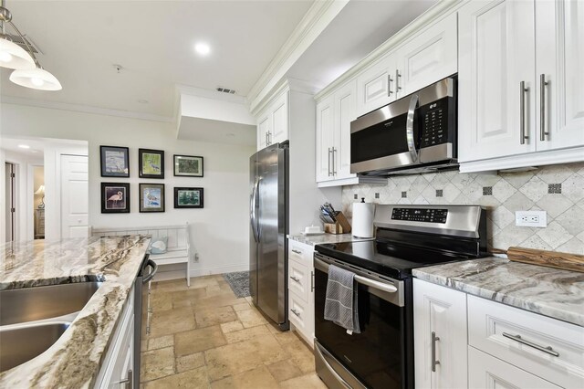 kitchen with crown molding, appliances with stainless steel finishes, tasteful backsplash, and stone tile flooring