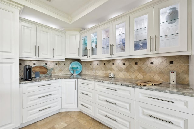 kitchen with ornamental molding, a tray ceiling, and light stone countertops