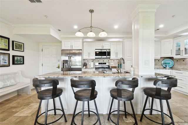 kitchen featuring crown molding, decorative columns, stainless steel appliances, backsplash, and white cabinetry