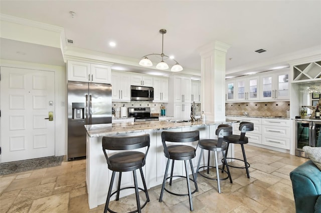 kitchen with wine cooler, white cabinetry, ornamental molding, appliances with stainless steel finishes, and stone tile flooring