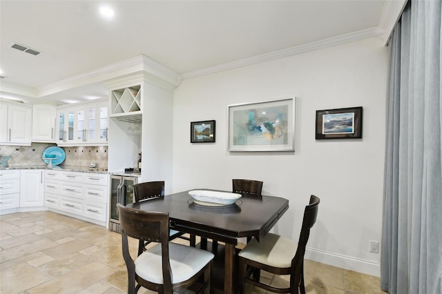 dining room with beverage cooler, stone tile floors, baseboards, visible vents, and crown molding