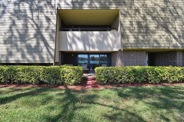 view of exterior entry with a yard and brick siding