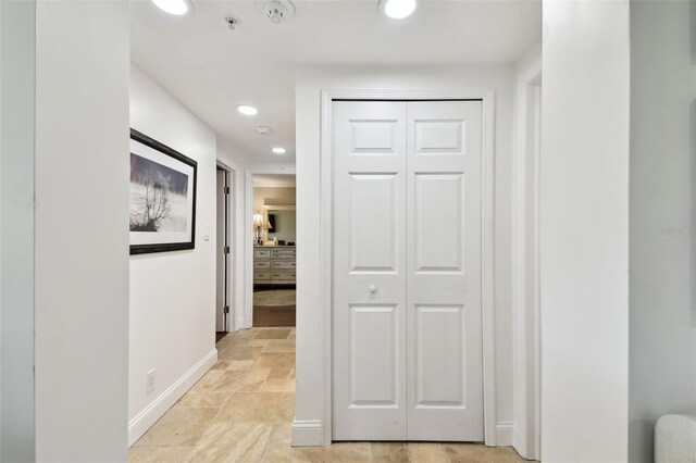 corridor featuring recessed lighting, stone finish floor, and baseboards