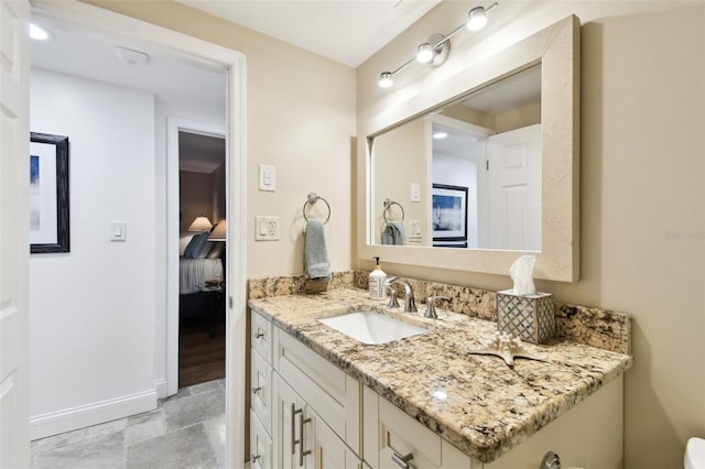 bathroom with stone finish flooring, connected bathroom, vanity, and baseboards