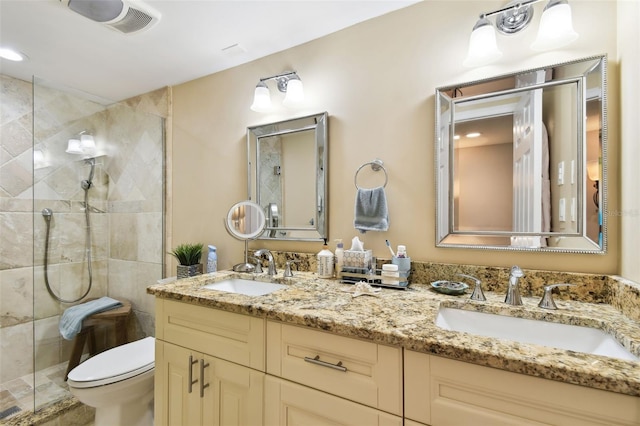 bathroom with double vanity, a stall shower, a sink, and toilet