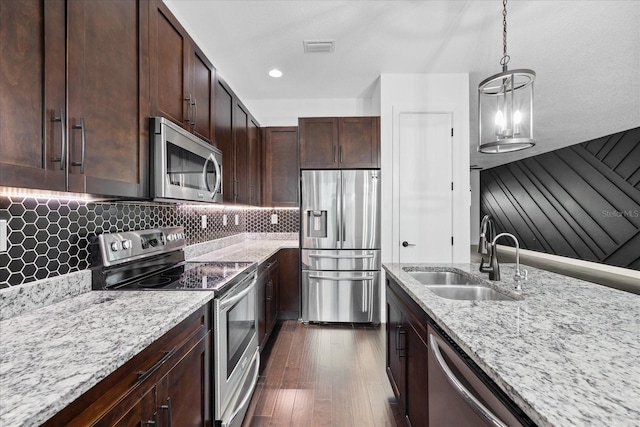 kitchen featuring a sink, light stone counters, decorative light fixtures, appliances with stainless steel finishes, and decorative backsplash