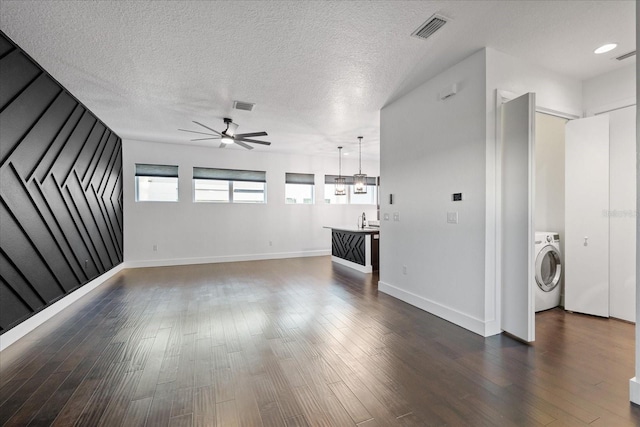 unfurnished living room featuring visible vents, washer / clothes dryer, ceiling fan, and dark wood-style flooring