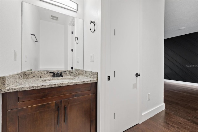 bathroom featuring visible vents, baseboards, wood finished floors, and vanity