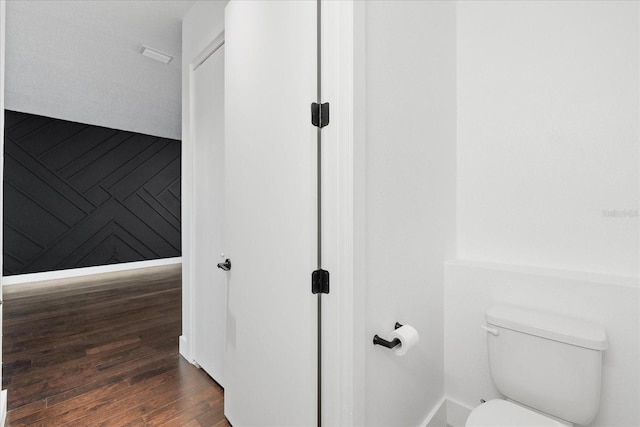 bathroom with wooden walls, toilet, and wood finished floors