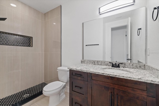 bathroom featuring vanity, tile patterned floors, toilet, and tiled shower