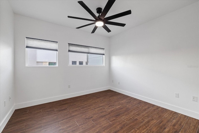 unfurnished room with dark wood finished floors, a ceiling fan, and baseboards