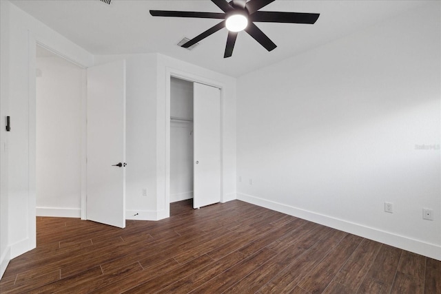 unfurnished bedroom featuring a closet, a ceiling fan, dark wood-type flooring, and baseboards