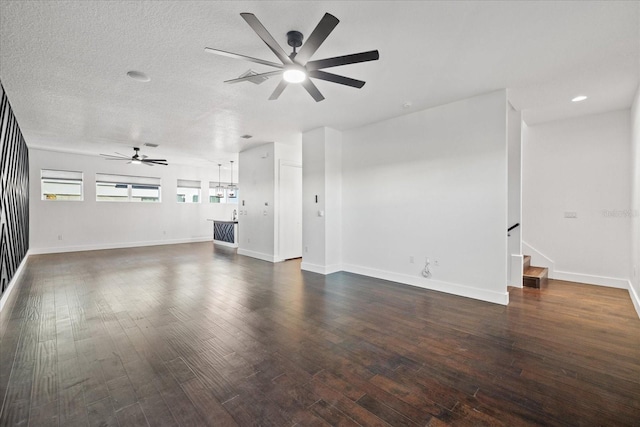 unfurnished living room with a ceiling fan, a textured ceiling, dark wood finished floors, stairway, and baseboards