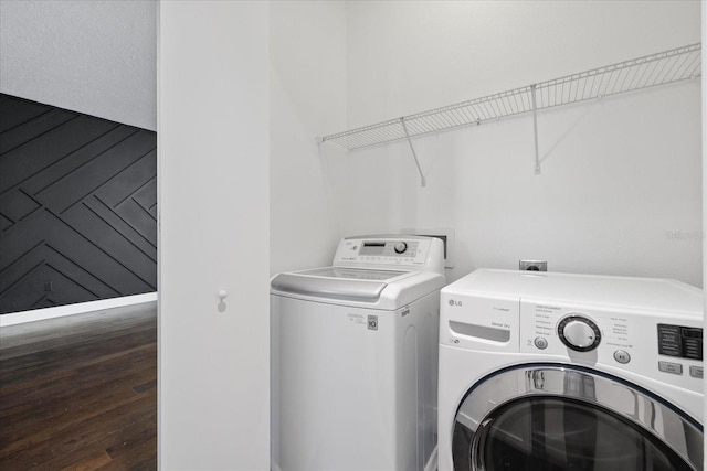 laundry room featuring washing machine and clothes dryer, wooden walls, laundry area, and wood finished floors