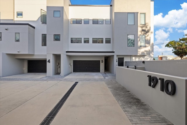 townhome / multi-family property featuring fence, a garage, driveway, and stucco siding