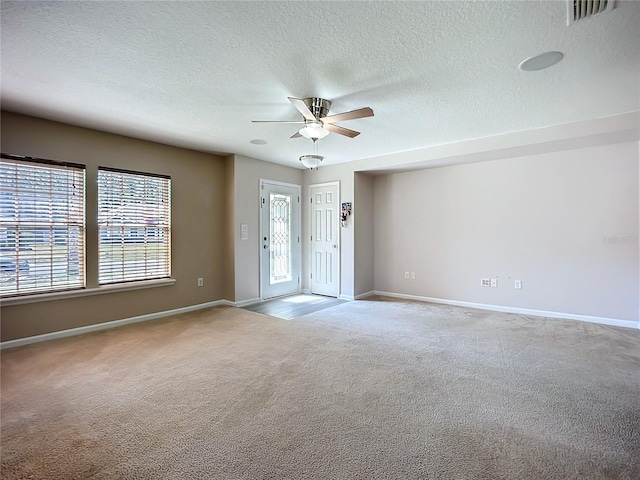 spare room featuring carpet flooring, visible vents, baseboards, and a ceiling fan