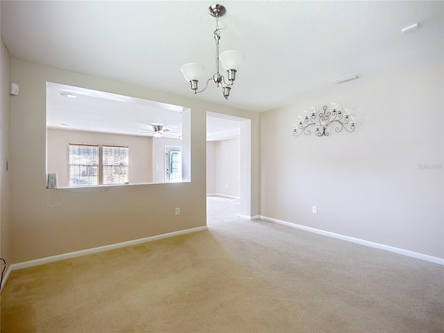 carpeted spare room featuring baseboards and ceiling fan with notable chandelier