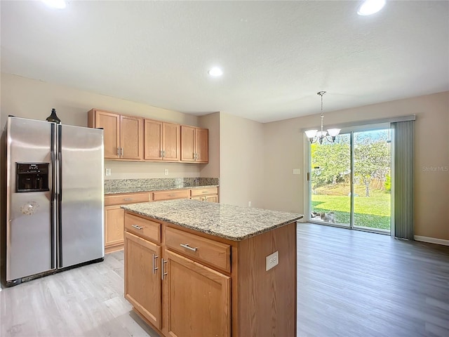 kitchen featuring stainless steel refrigerator with ice dispenser, light stone counters, a kitchen island, light wood-style floors, and an inviting chandelier