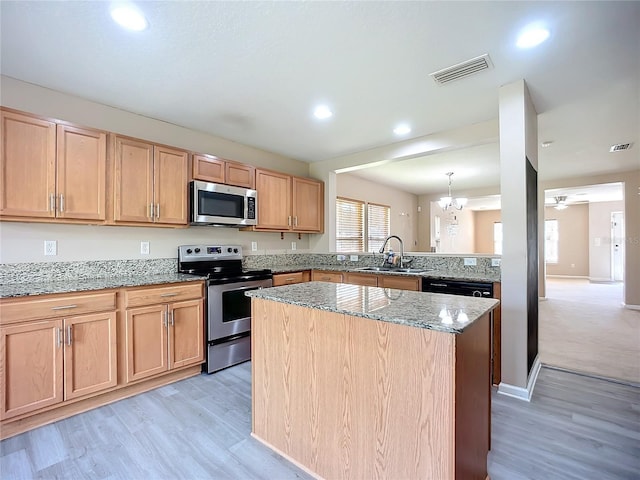 kitchen with a sink, light stone counters, visible vents, and stainless steel appliances