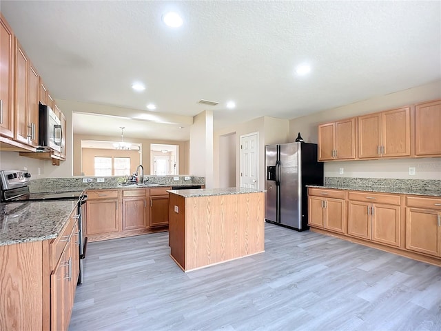 kitchen with visible vents, a sink, light stone counters, appliances with stainless steel finishes, and light wood finished floors