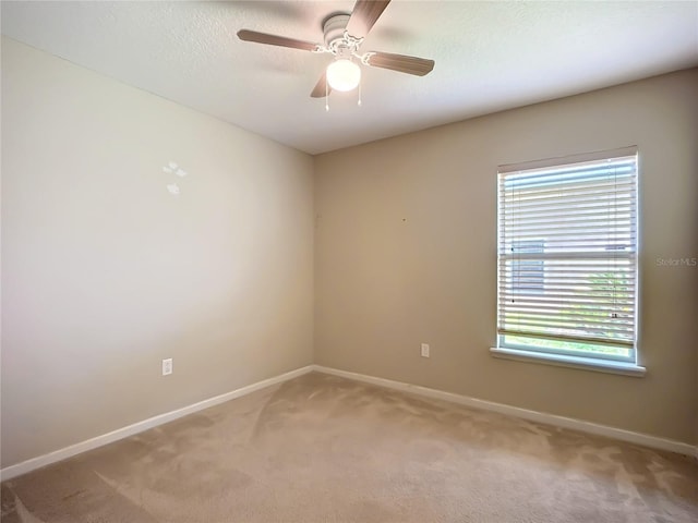 spare room featuring baseboards, light colored carpet, and a ceiling fan