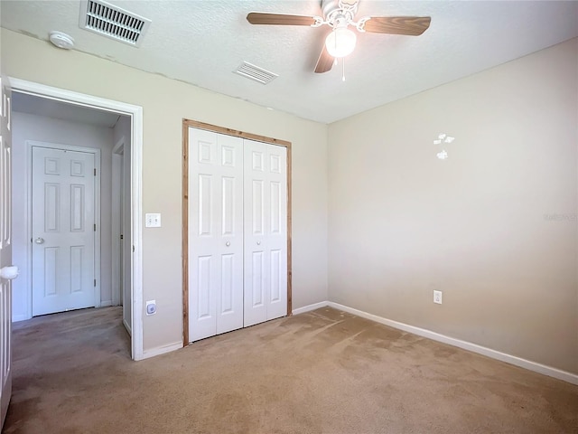 unfurnished bedroom featuring light colored carpet, visible vents, a closet, and a textured ceiling