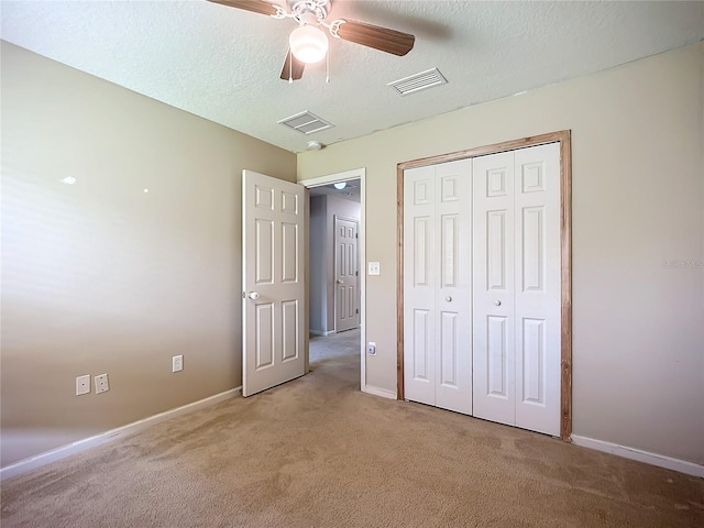 unfurnished bedroom with visible vents, light colored carpet, a closet, and a textured ceiling