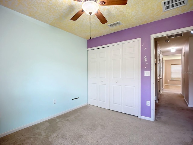 unfurnished bedroom featuring a closet, visible vents, carpet flooring, and a textured ceiling